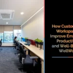 Minimalist customized office workspace with long shared desks, ergonomic chairs, indoor plants, and natural lighting from large windows. Overlay text reads: ‘How Customized Workspaces Improve Employee Productivity and Well-Being.