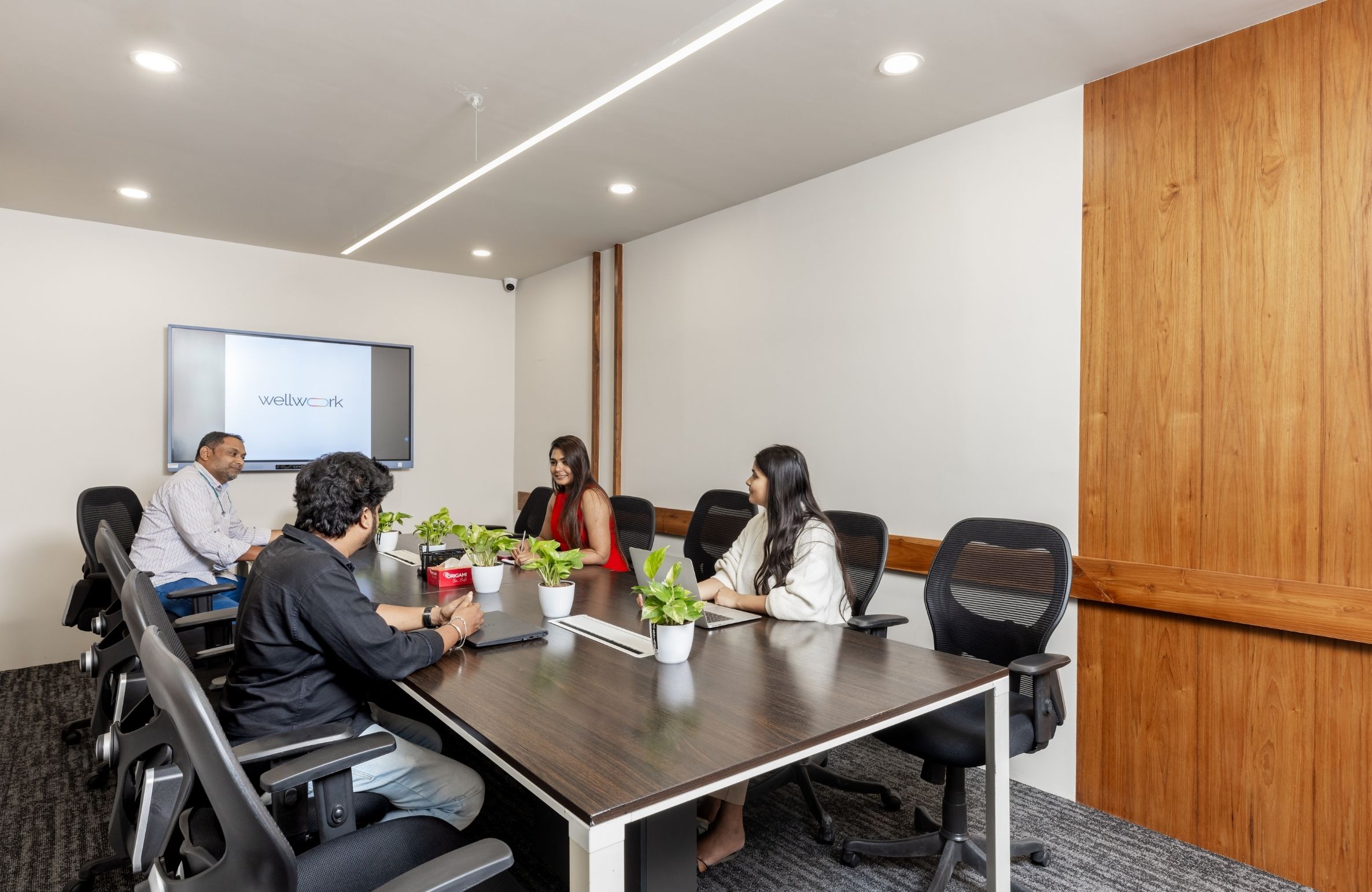 Modern office space in Gachibowli with a team meeting around a conference table in a bright, fully furnished workspace designed for growing teams.